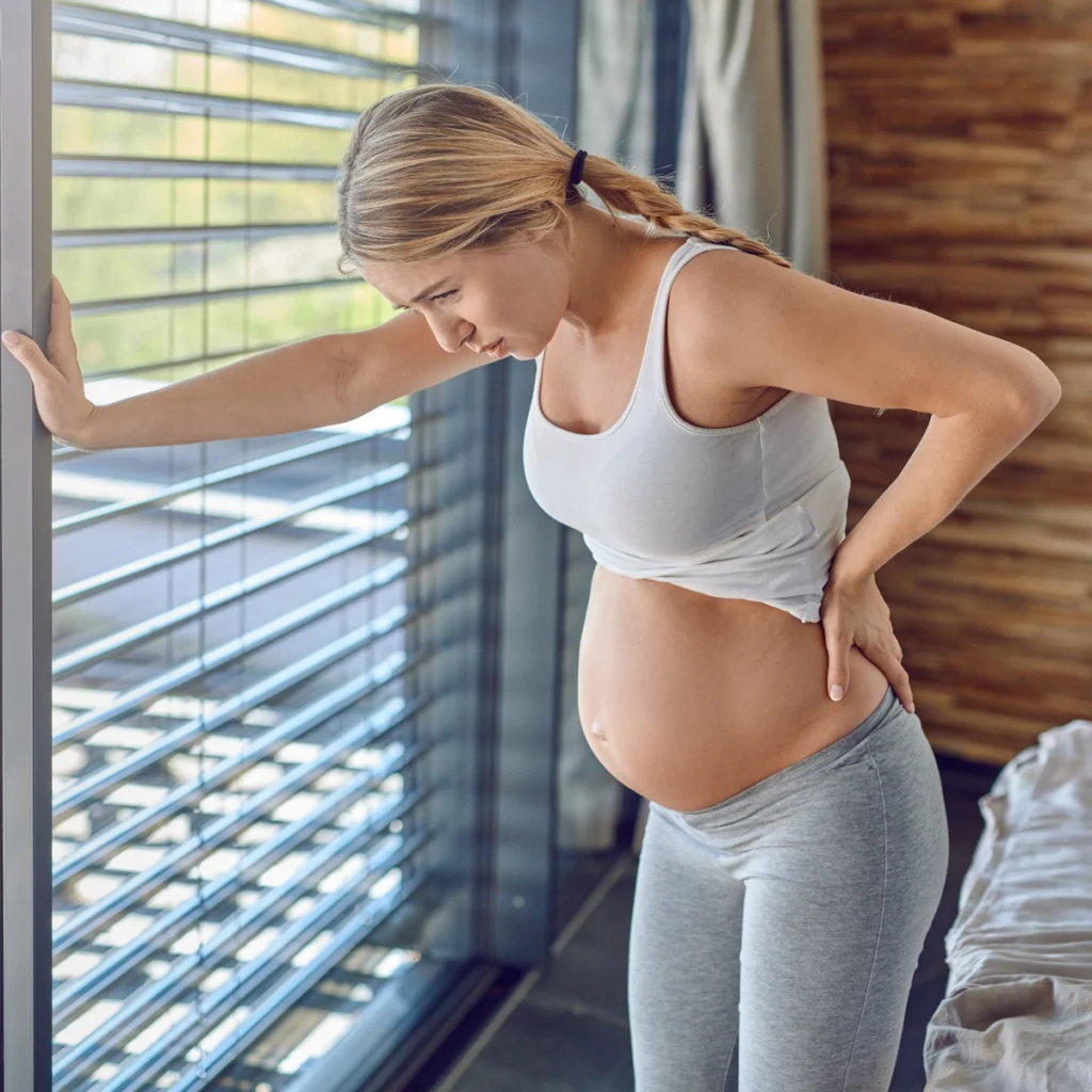 Photo d'une femme enceinte qui se tient conte la fenêtre